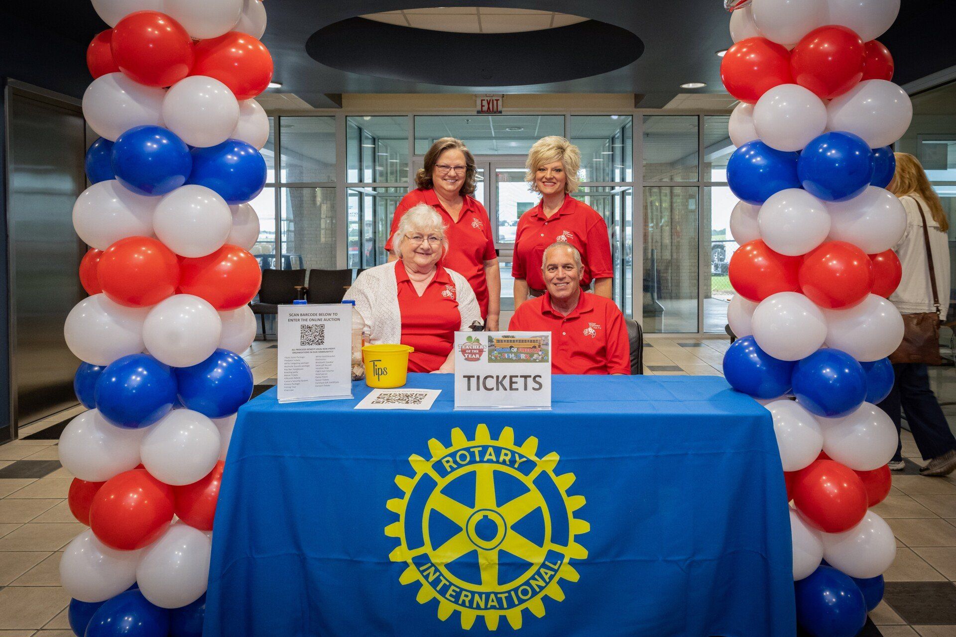 A group of women are sitting at a table with balloons around it.