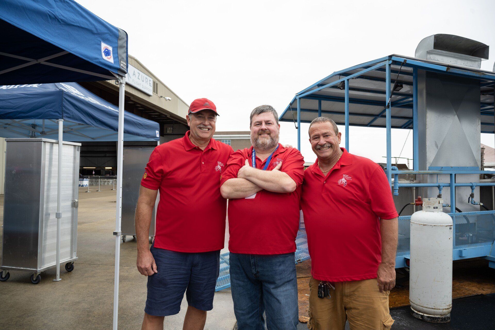 Three men in red shirts are posing for a picture.