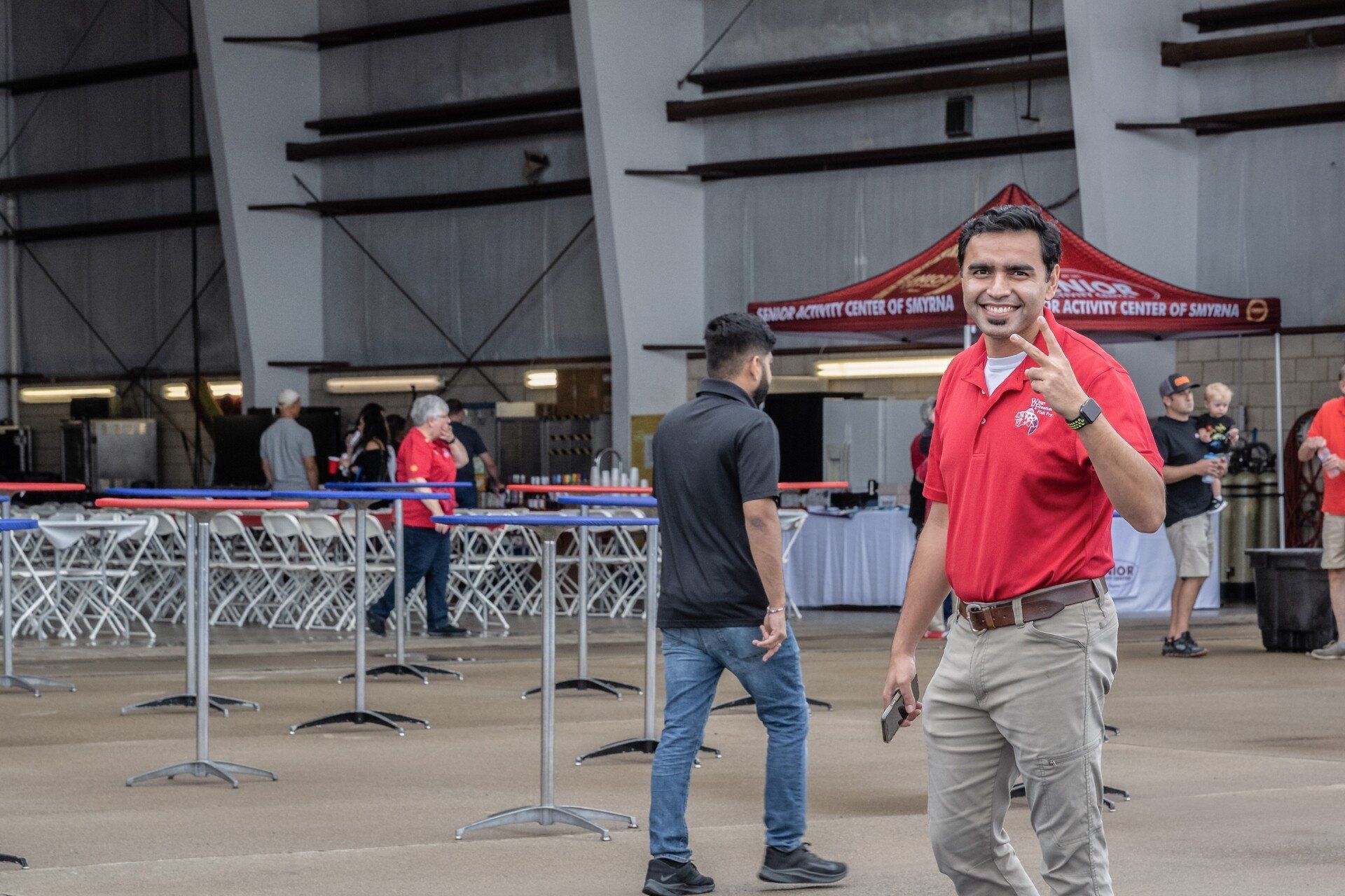 A man in a red shirt is standing in front of a crowd of people.