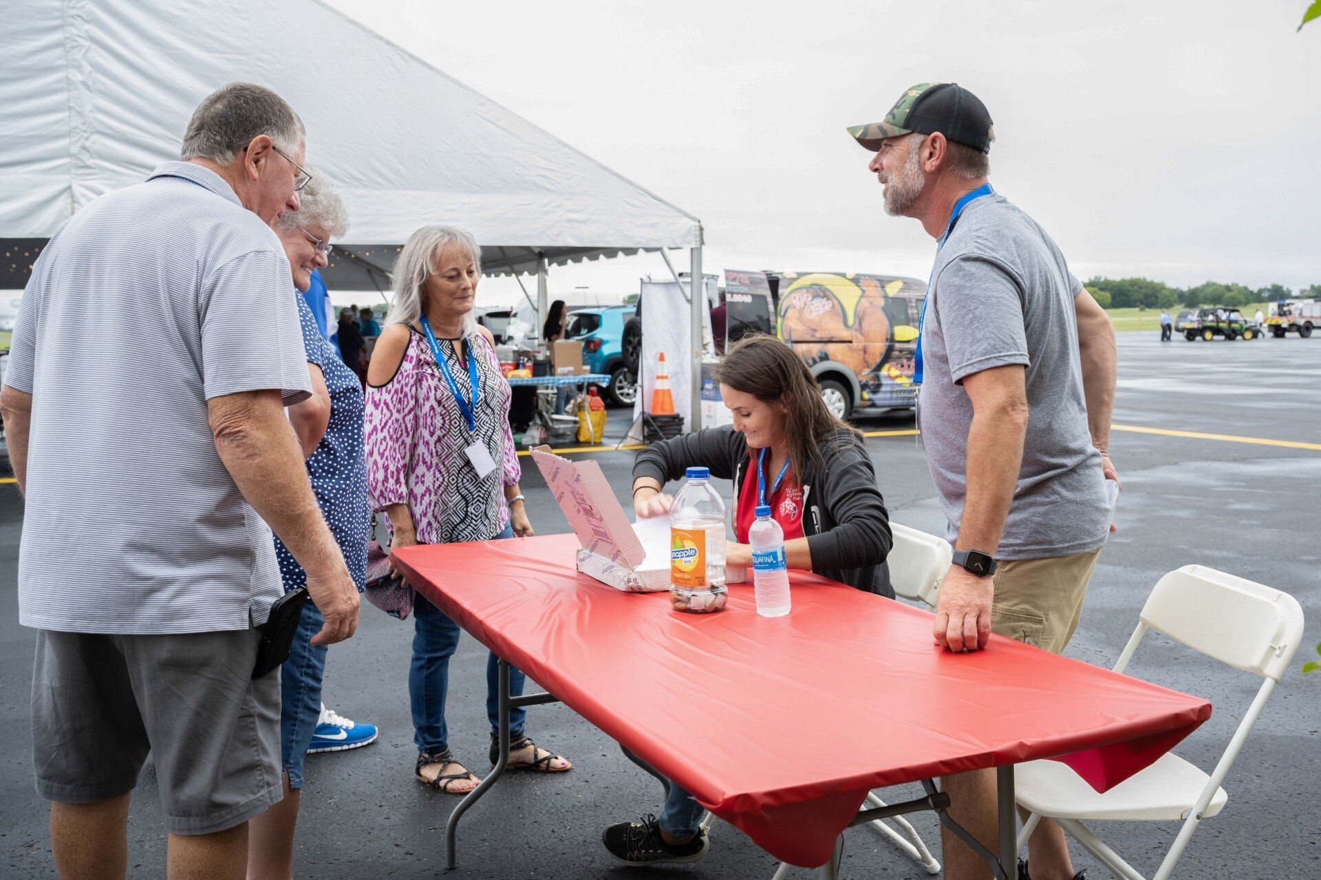 A group of people are standing around a table in a parking lot.