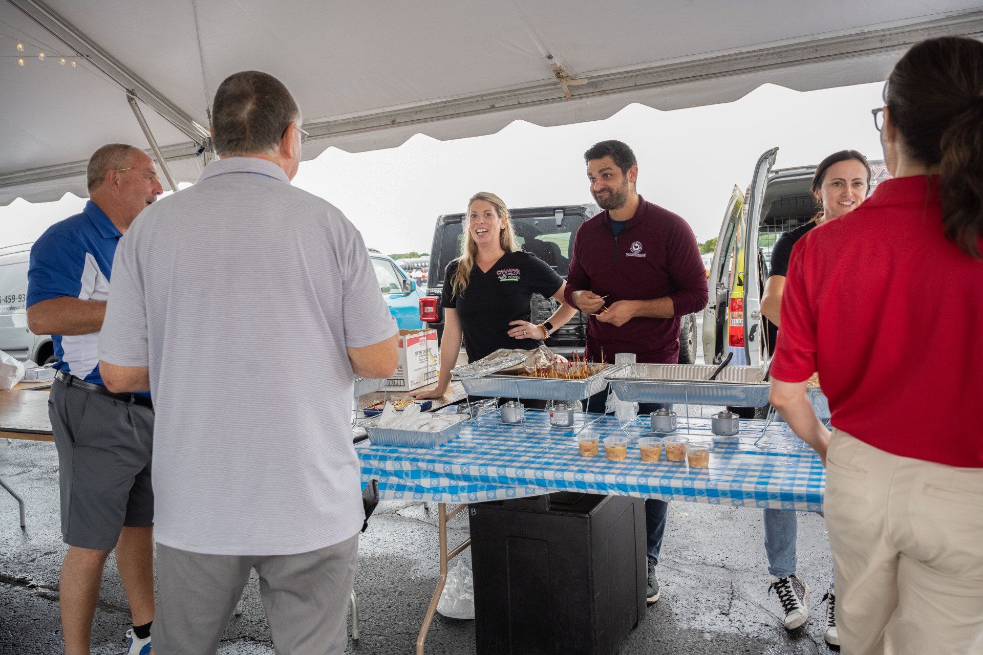 A group of people are standing around a table under a tent.