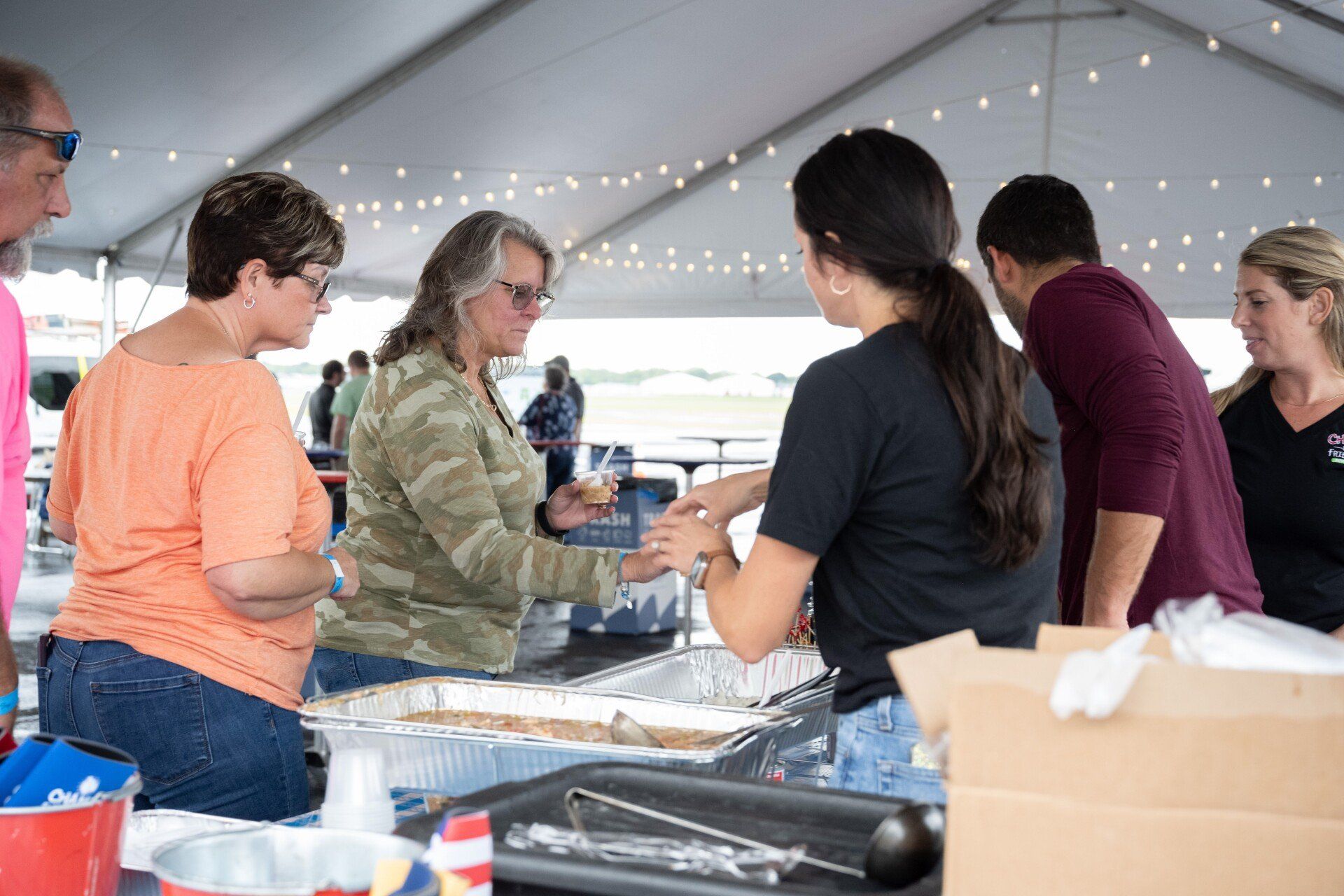 A group of people are standing around a table under a tent.