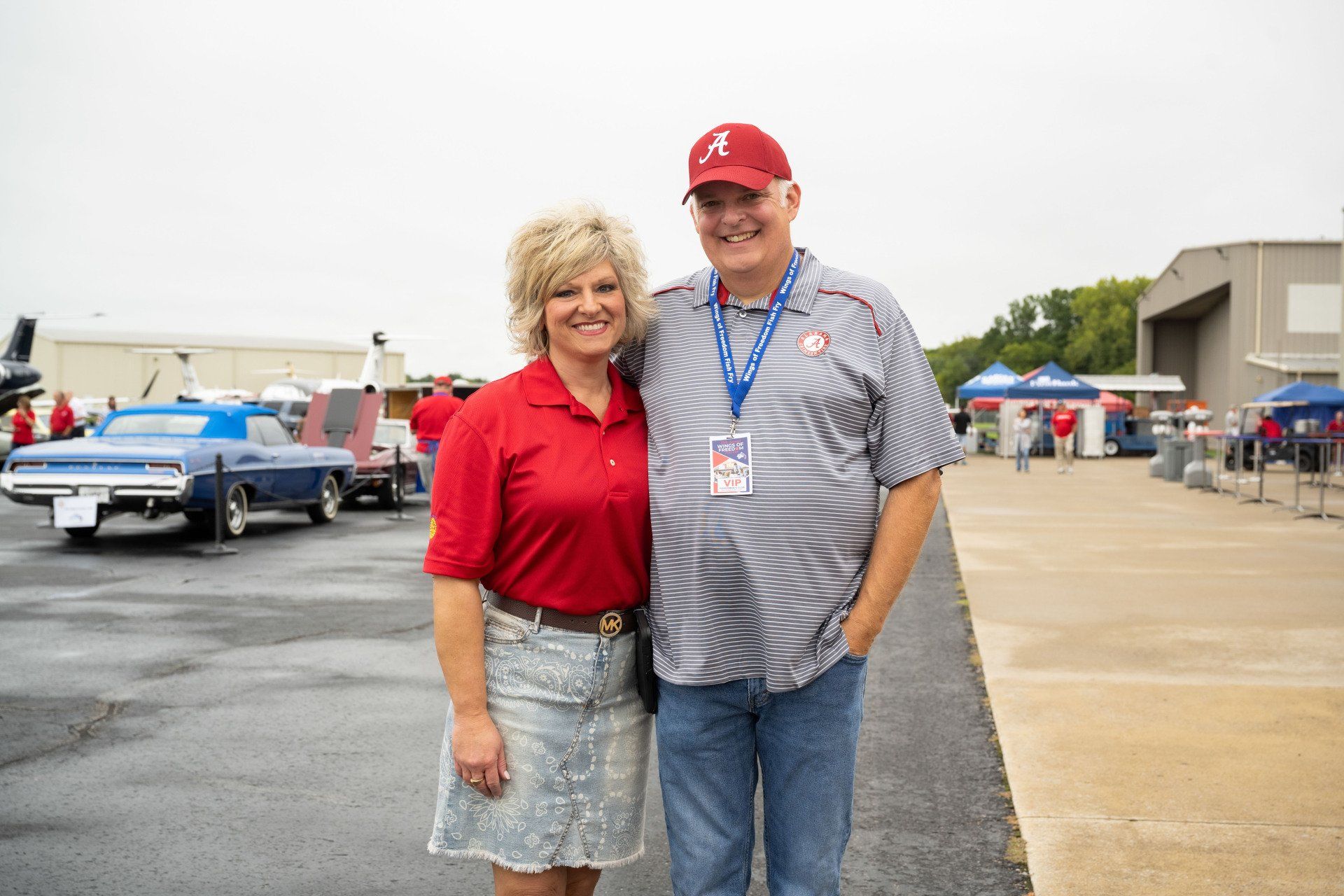 A man and a woman are posing for a picture in a parking lot.