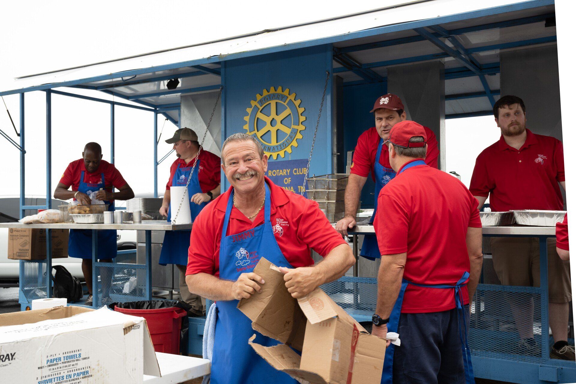 A group of men are standing in front of a food truck.
