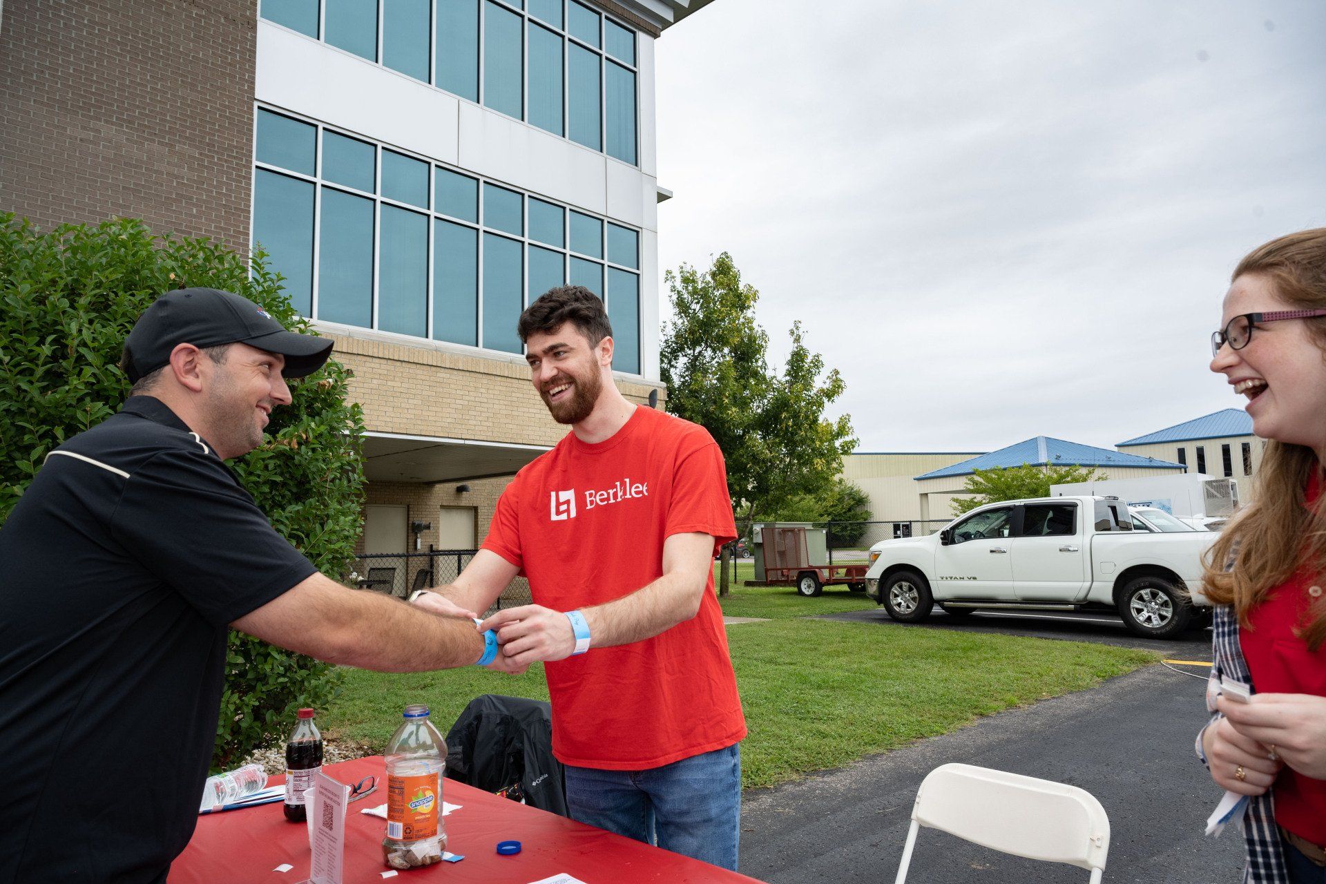A man in a red shirt is shaking hands with a man in a black shirt.