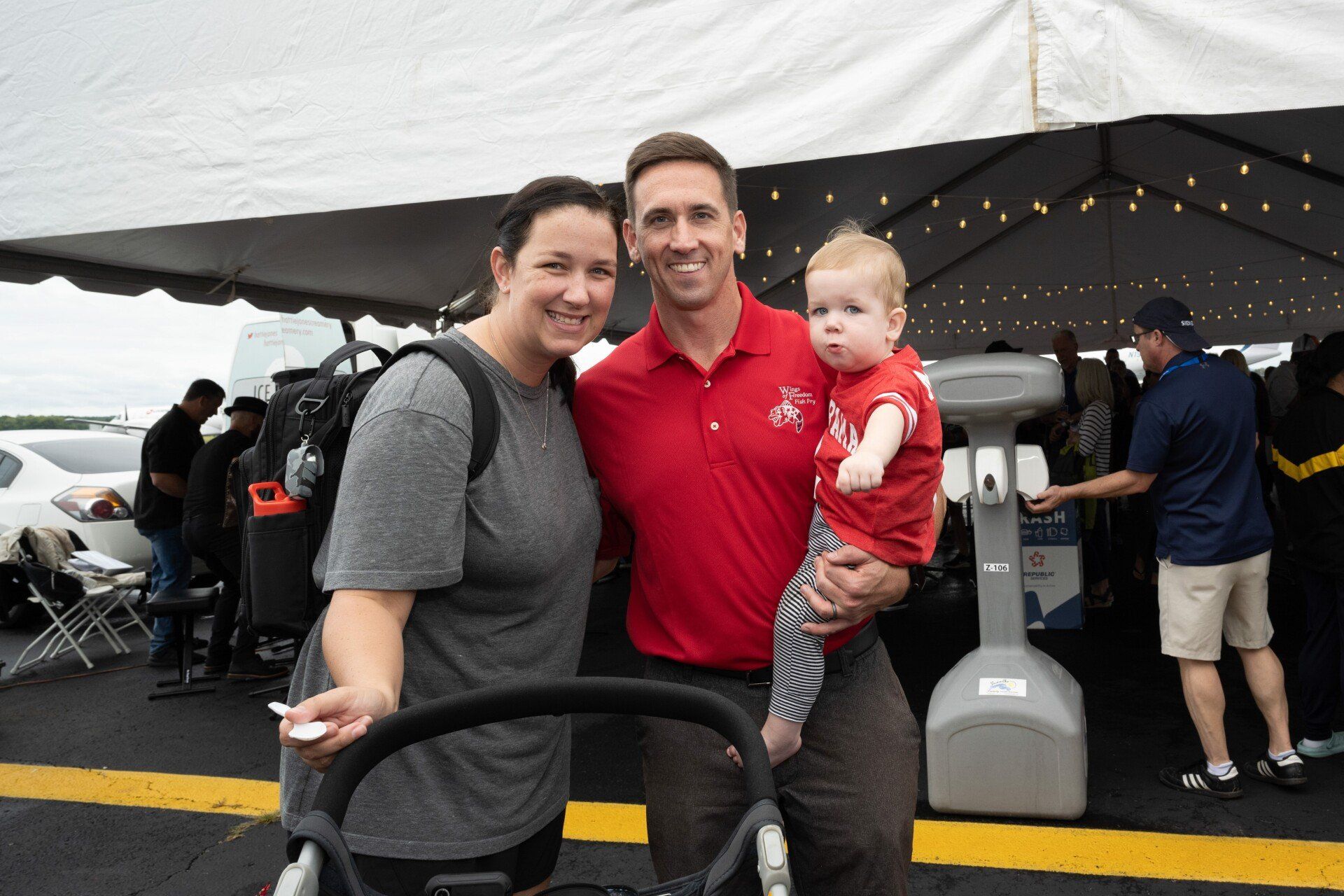 A man and woman are posing for a picture with a baby in a stroller.