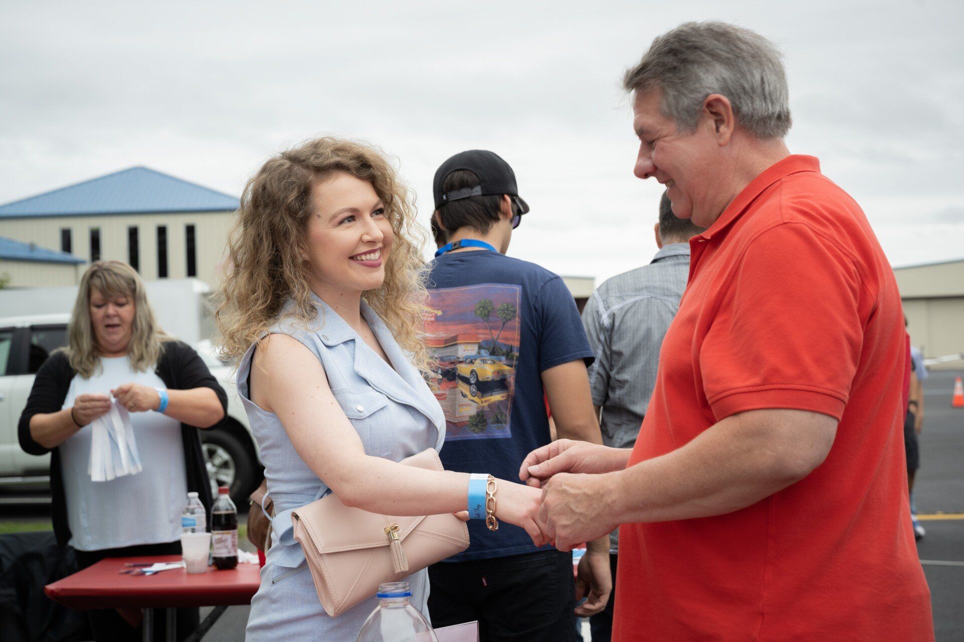 A man and a woman are shaking hands in a parking lot.