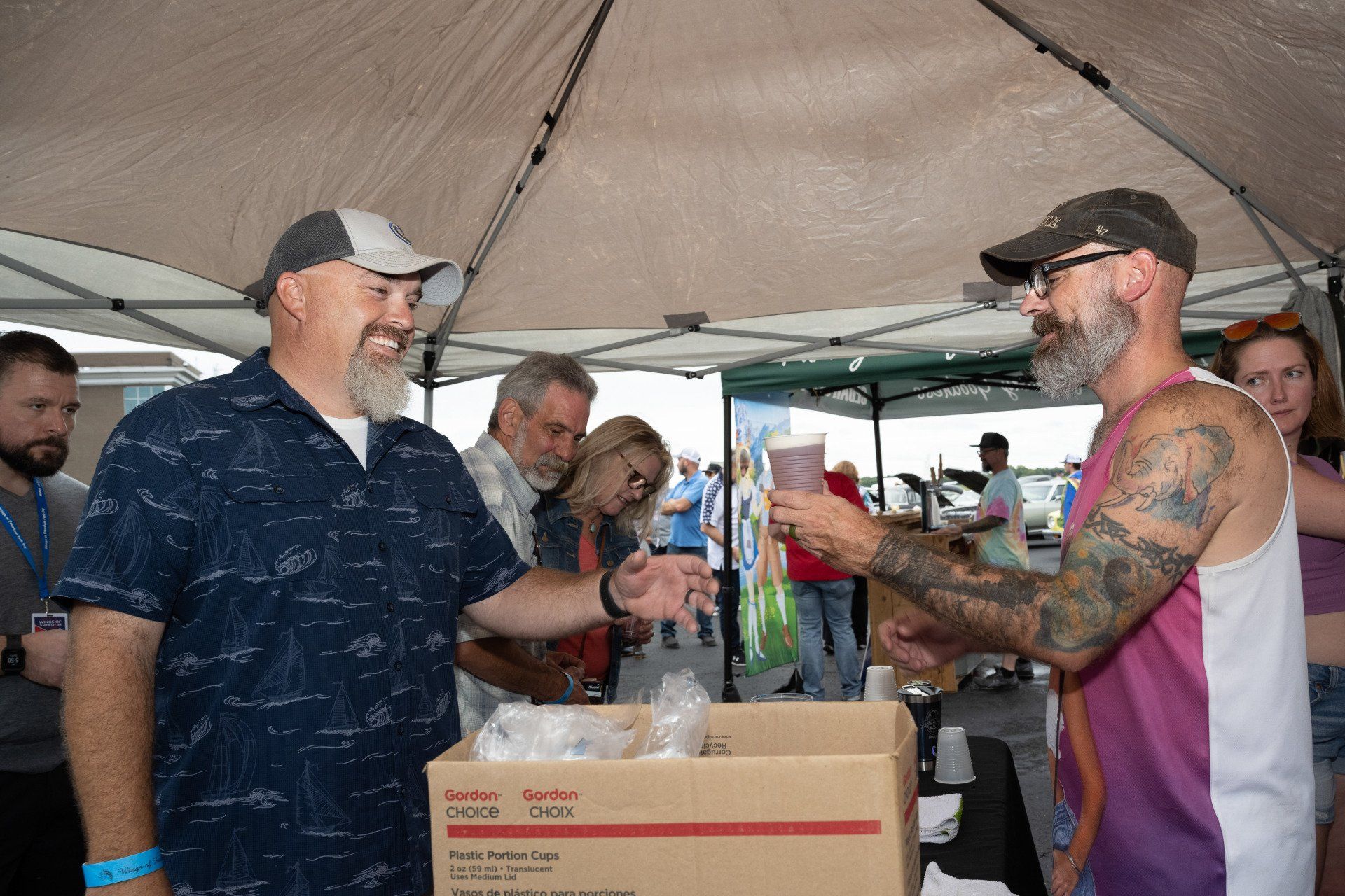 A group of men are standing under a tent talking to each other.