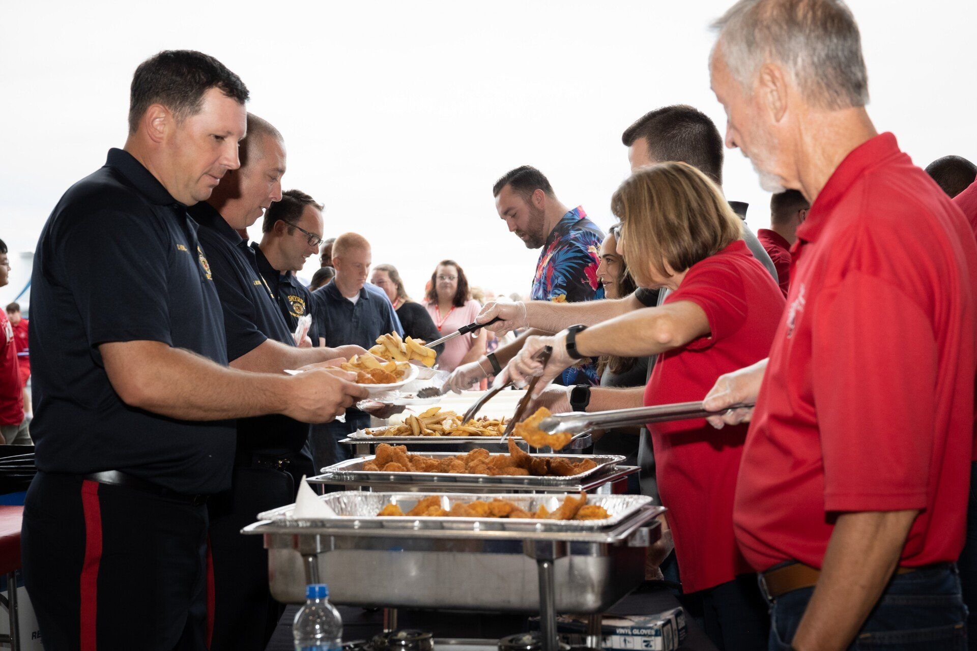 A group of people are standing around a buffet line.