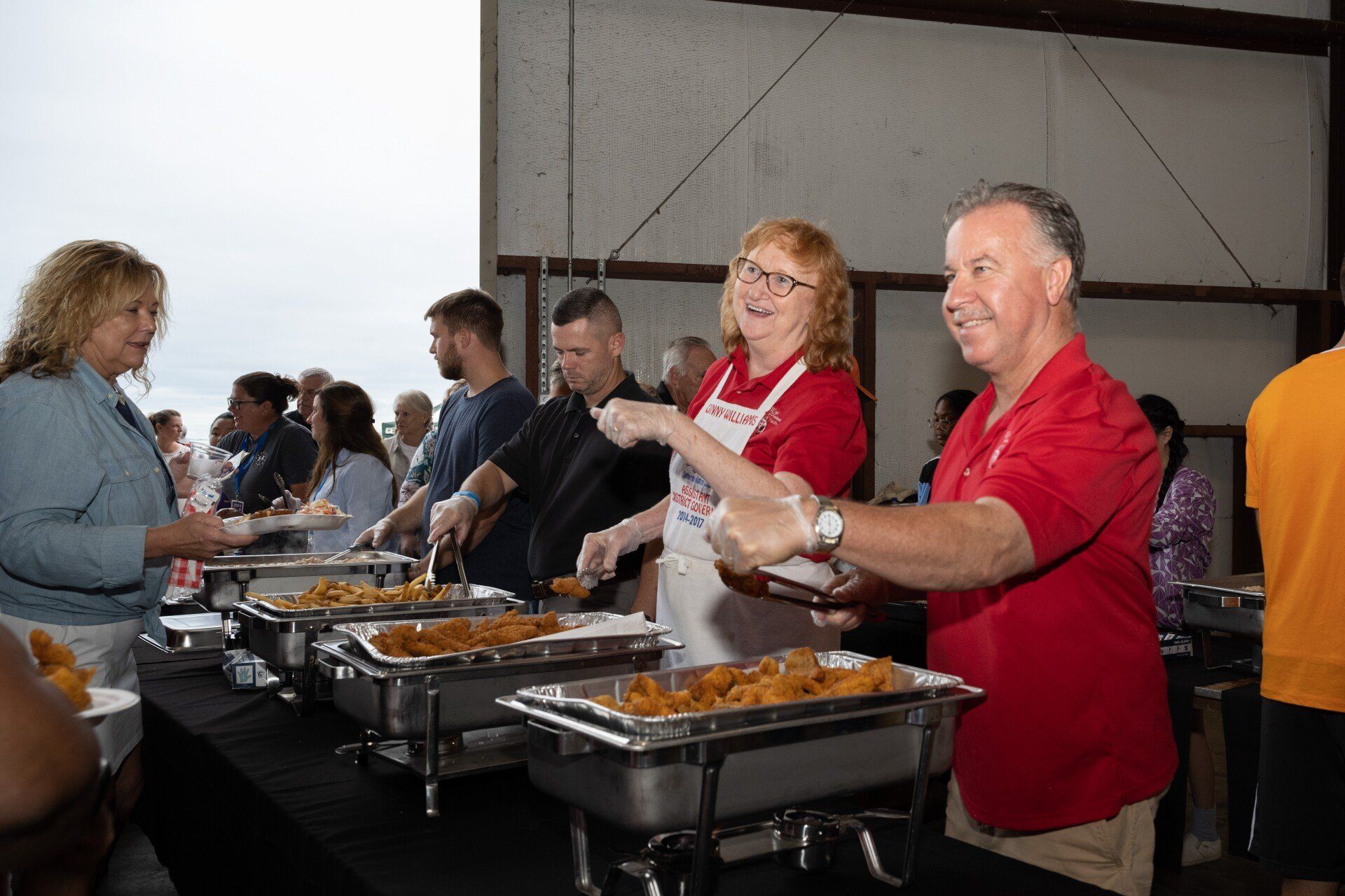 A group of people are standing around a table serving food.