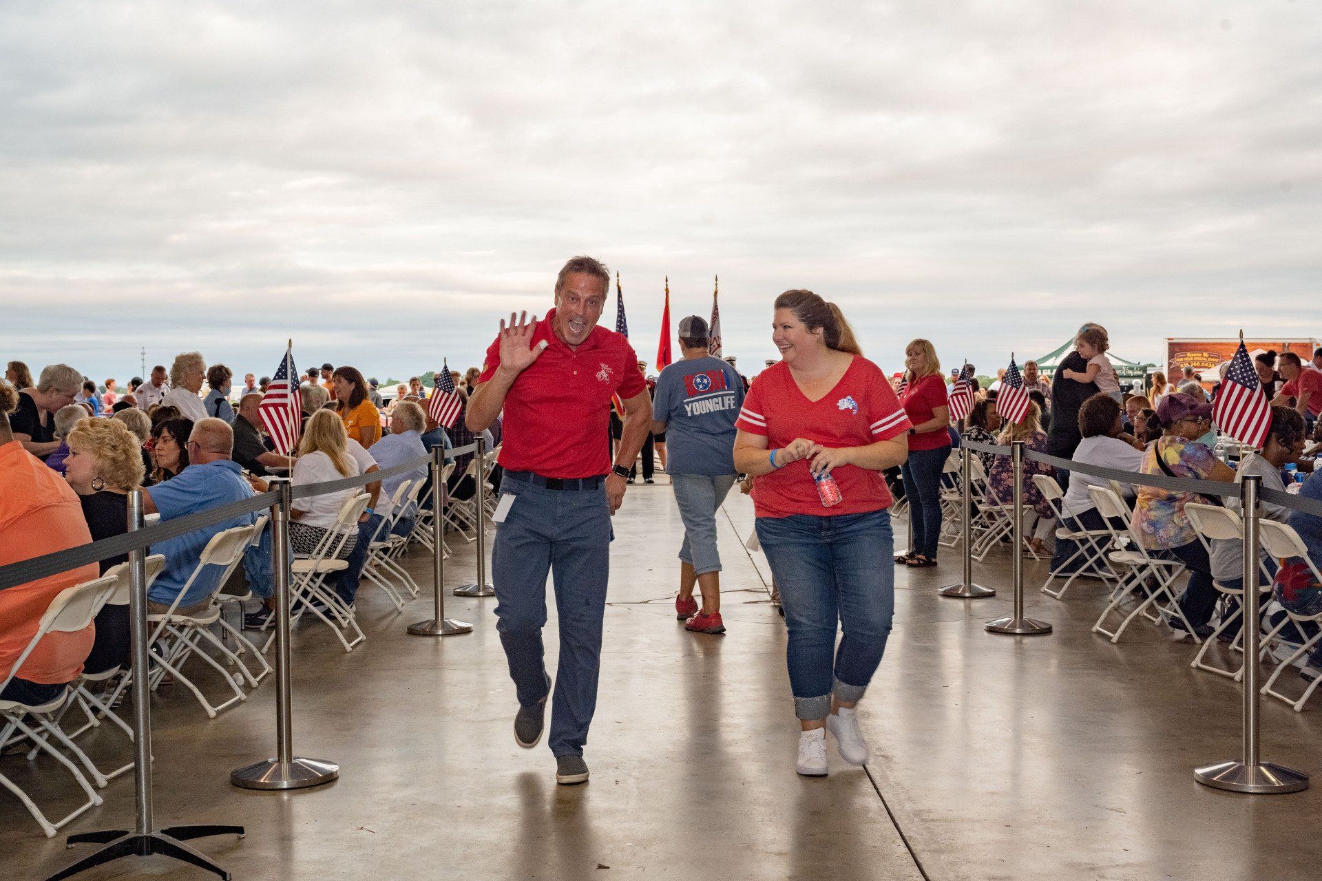 A man and a woman are walking through a crowd of people.