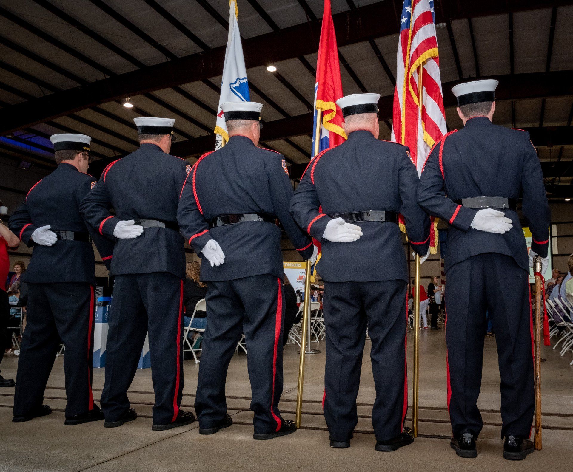 A group of men in uniform are standing in front of flags