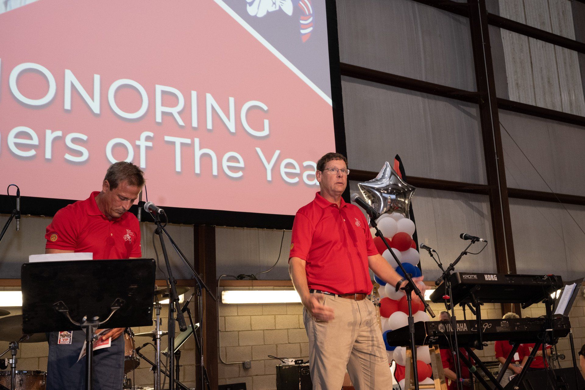Two men are standing in front of a large screen that says honoring ers of the year.