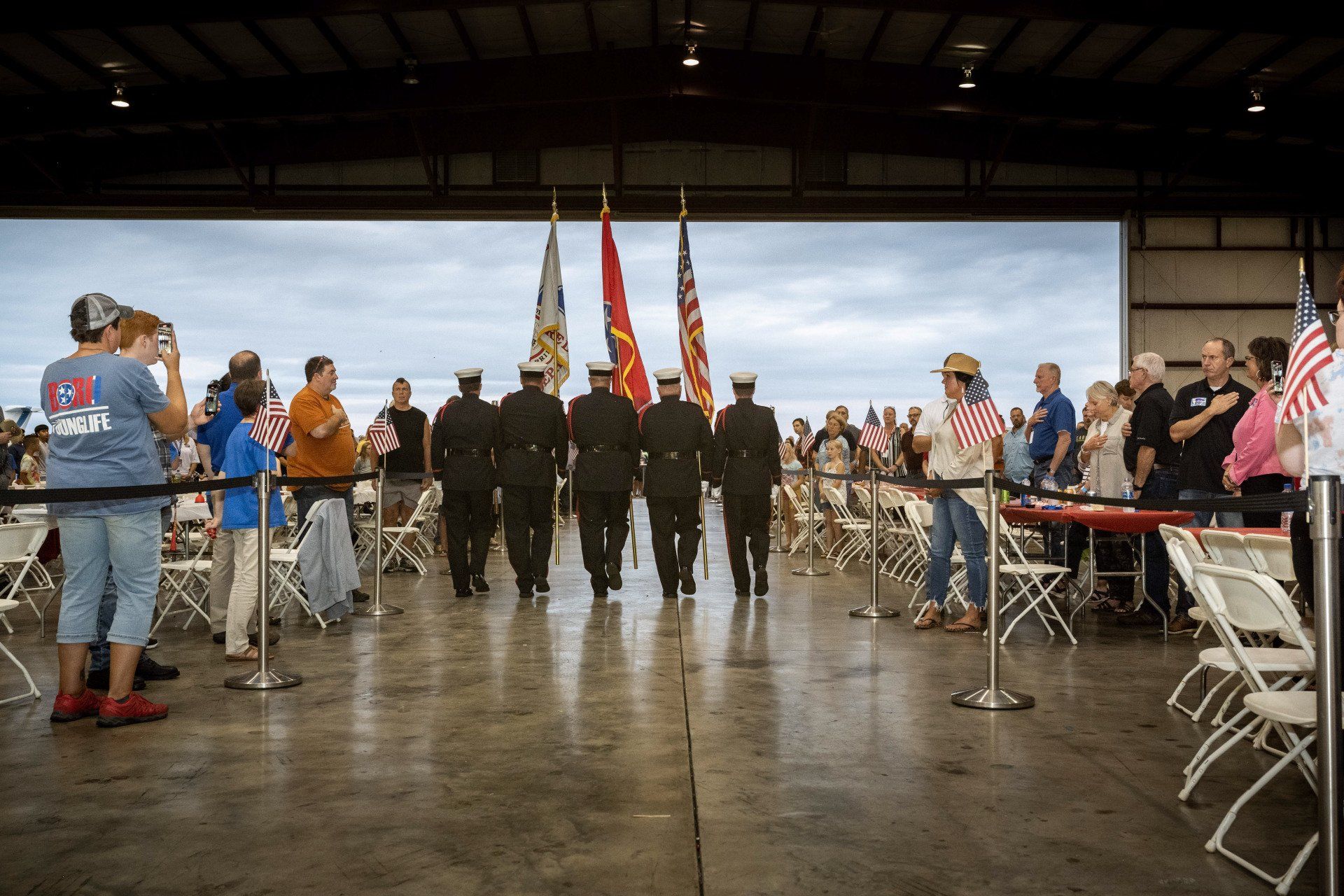 A group of men are walking in a line with flags.