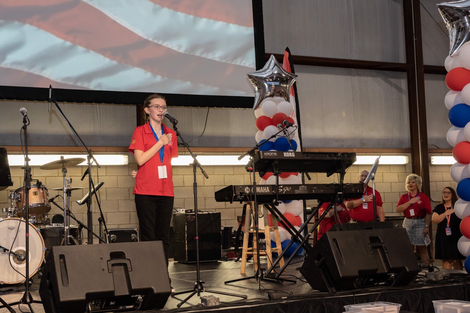 A girl is singing into a microphone on a stage.