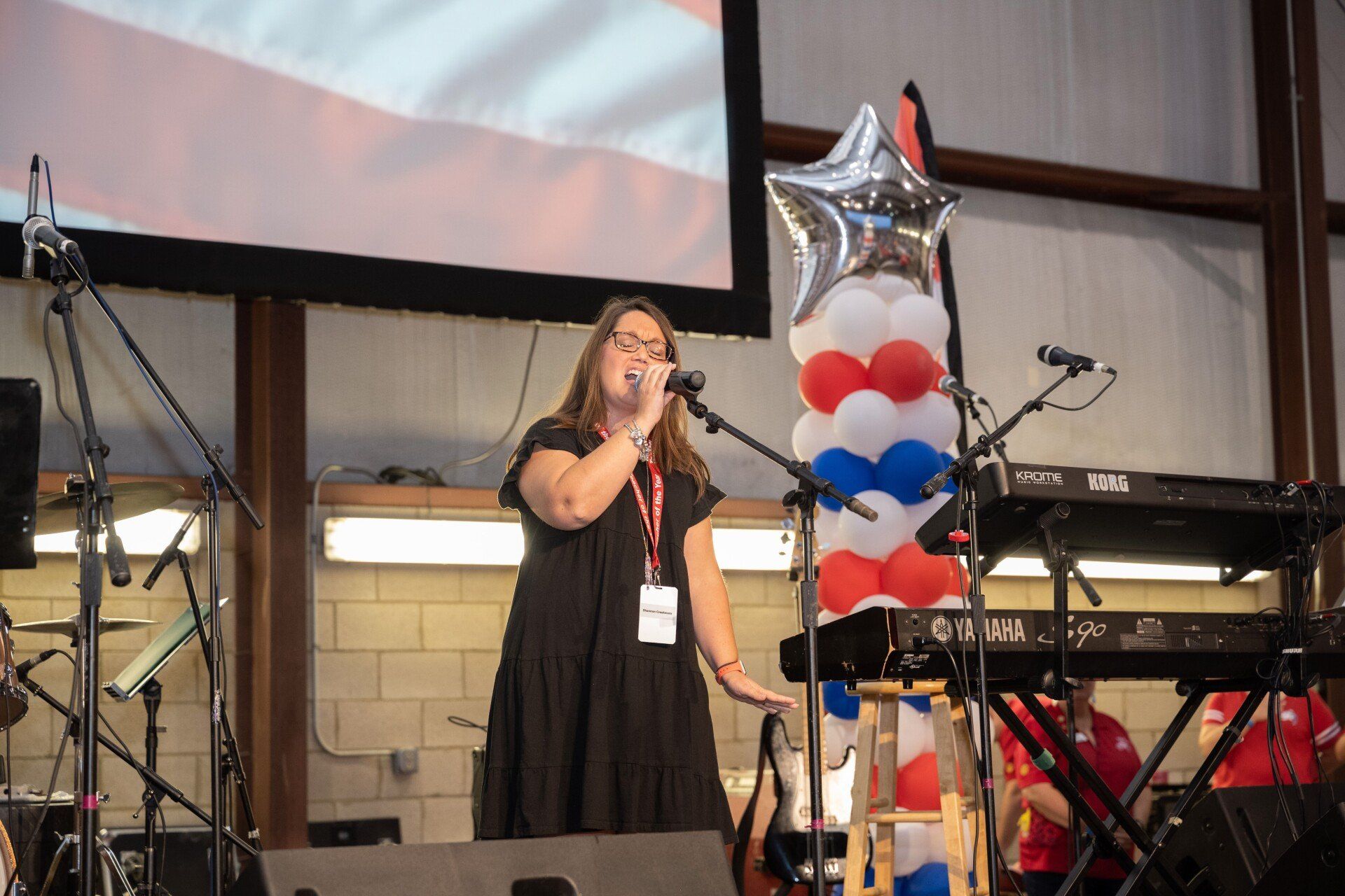 A woman is singing into a microphone on a stage.