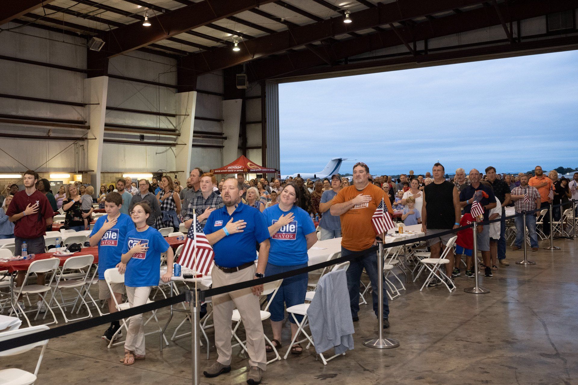 A group of people are standing in a room with their hands on their chests.