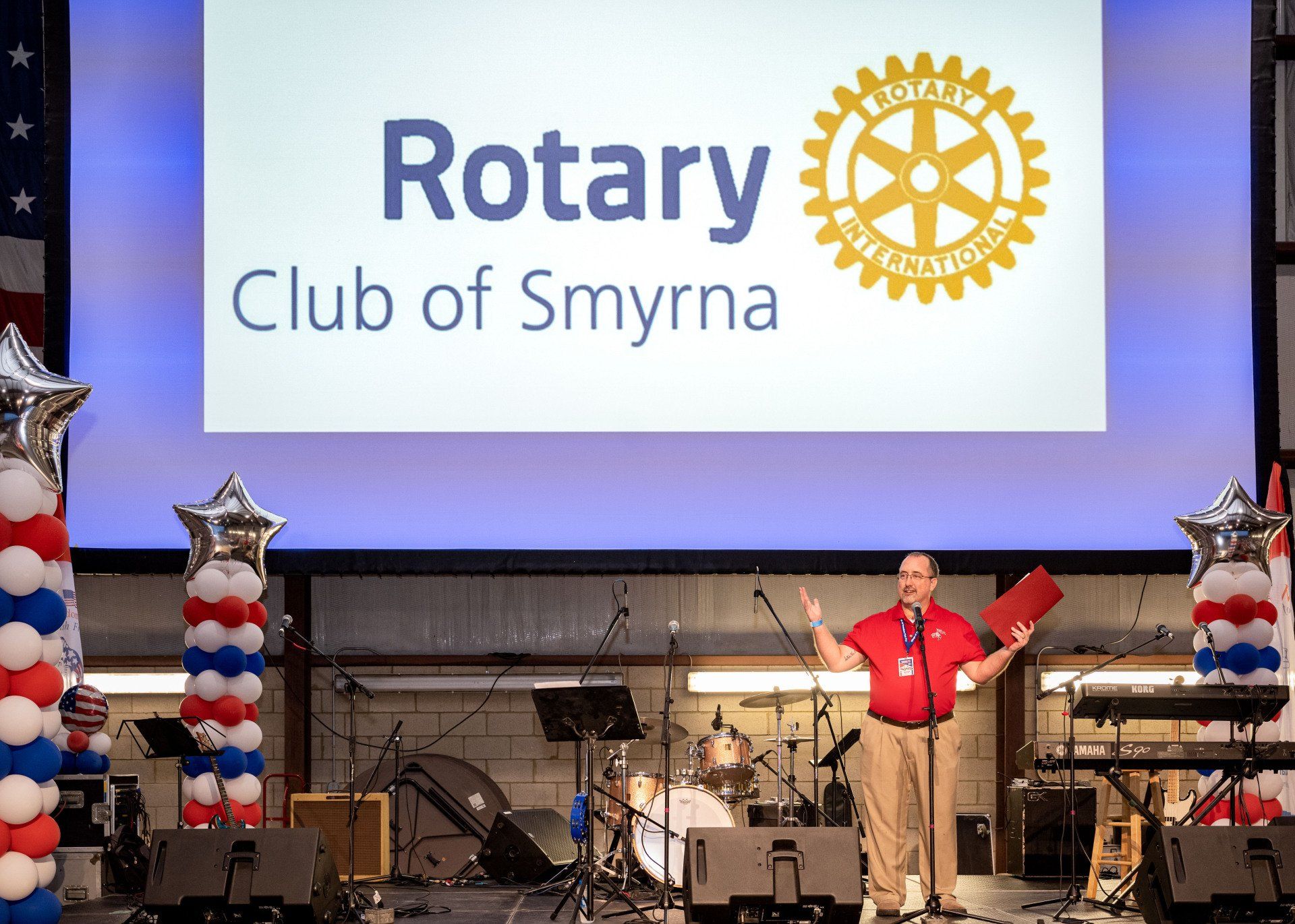 A man is standing in front of a large screen that says rotary club of smyrna