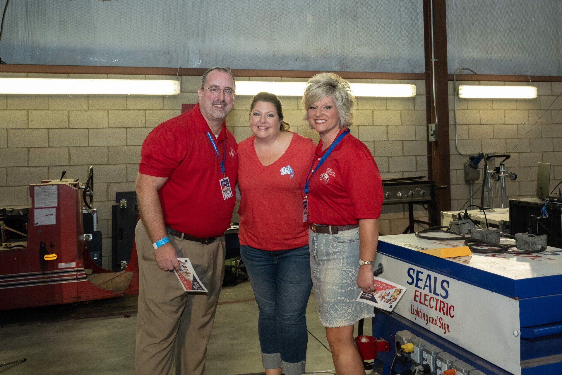 Three people posing for a picture in front of a seals machine