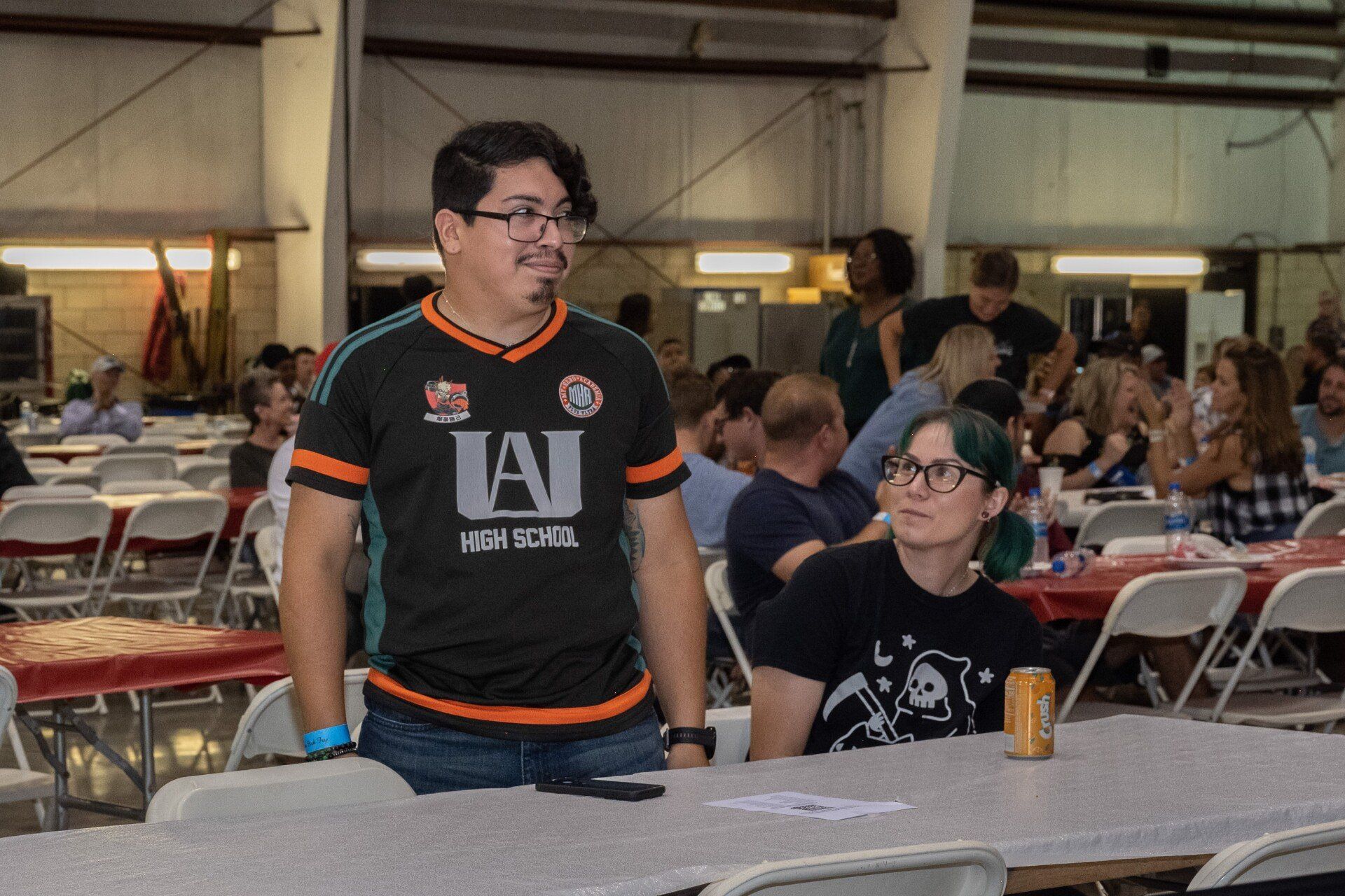A man wearing a jai jersey is standing in a crowded room.