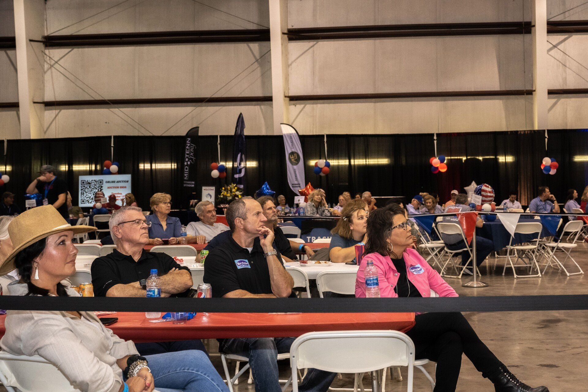 A group of people are sitting at tables in a large room.
