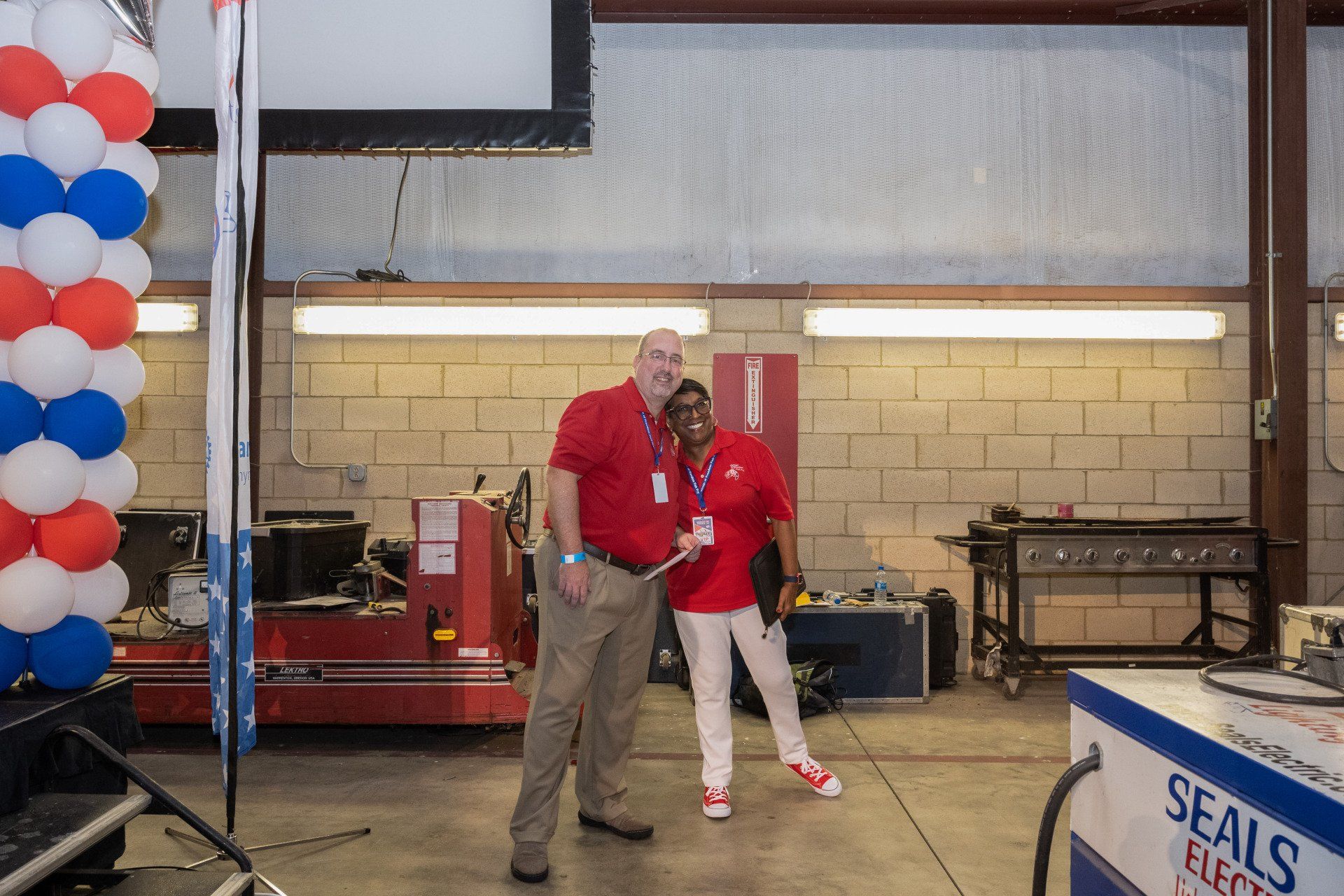 A man and a woman are standing in a room with balloons.