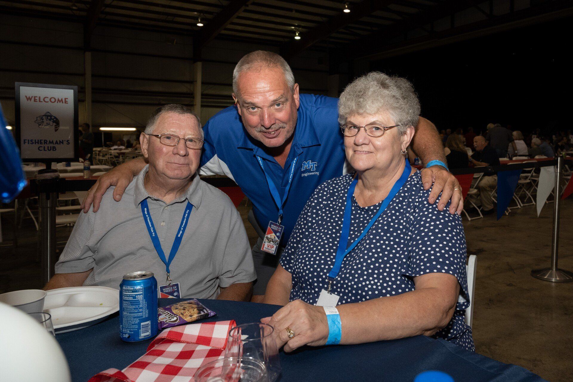 A group of people are posing for a picture while sitting at a table.