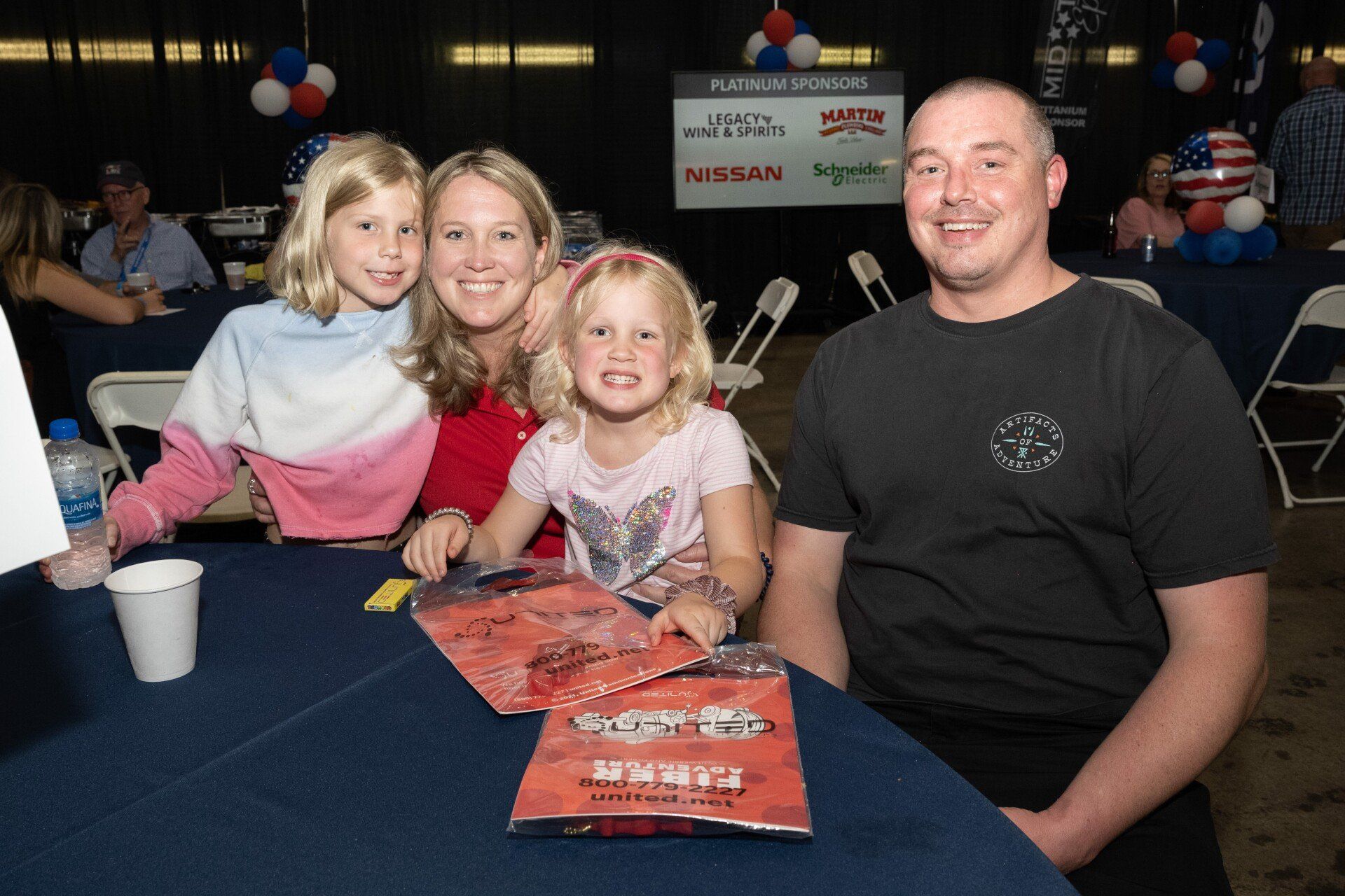 A man and two women are sitting at a table with two little girls.