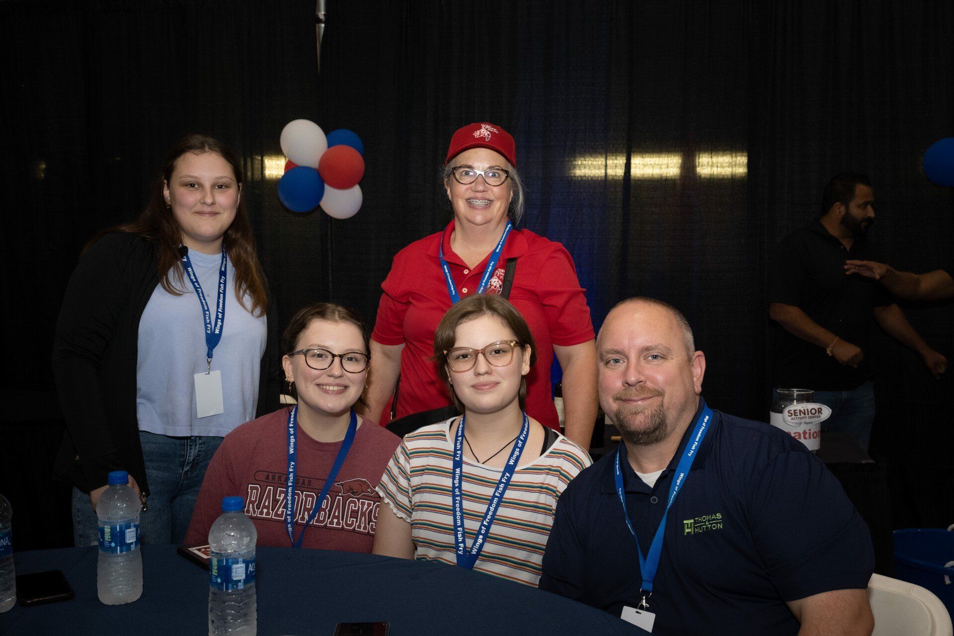 A group of people are posing for a picture while sitting at a table.