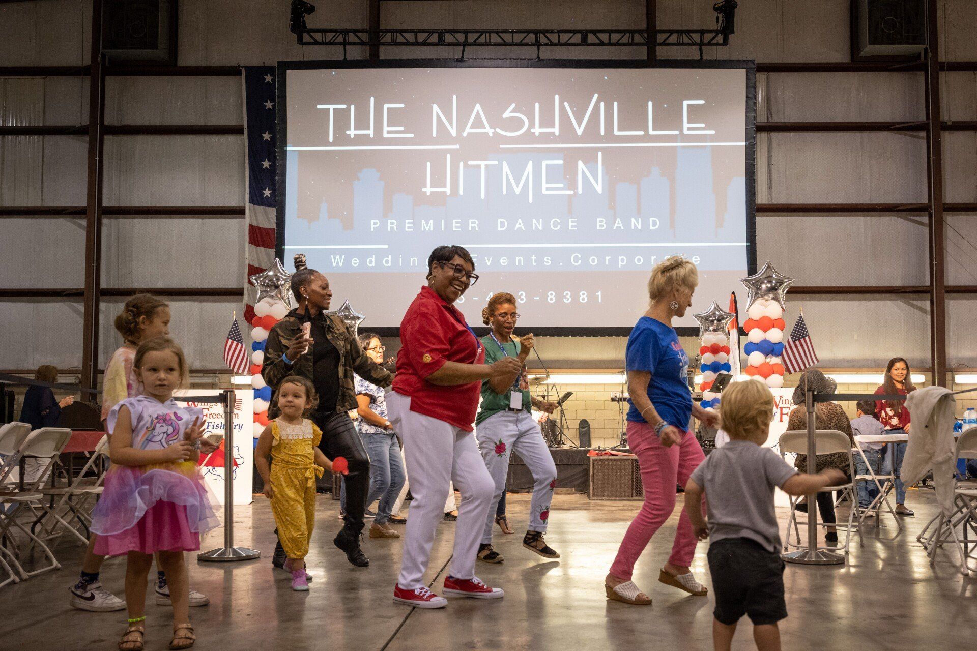 A group of people are dancing in front of a large screen.
