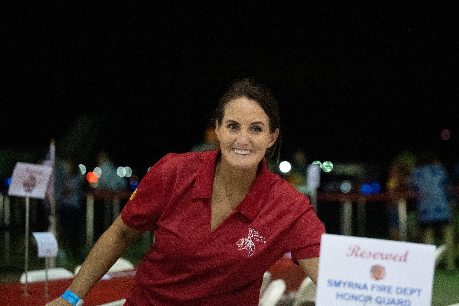 A woman in a red shirt is standing next to a reserved sign.