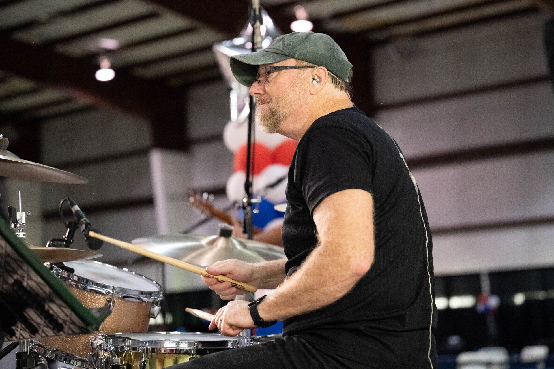 A man is playing drums in a room with balloons in the background.