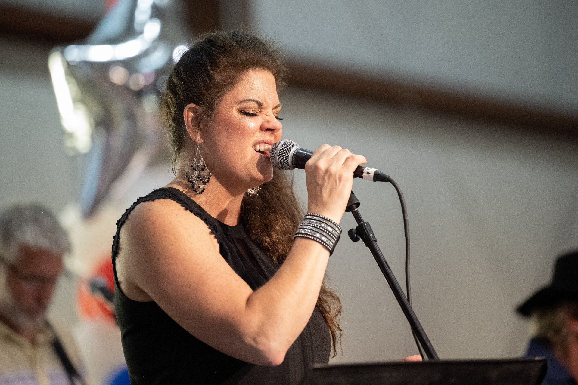 A woman is singing into a microphone while playing a keyboard.