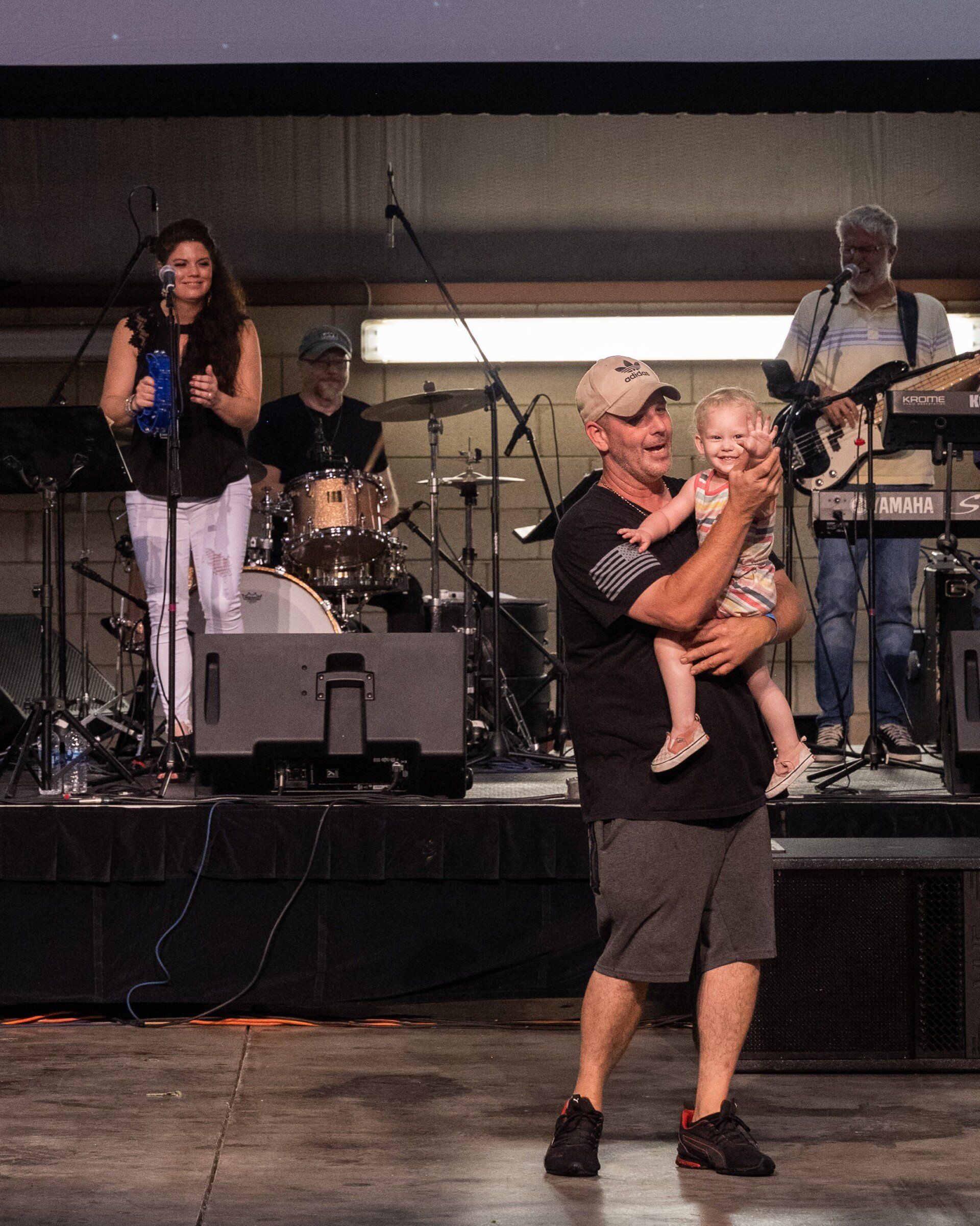A man is holding a baby on a stage in front of a band