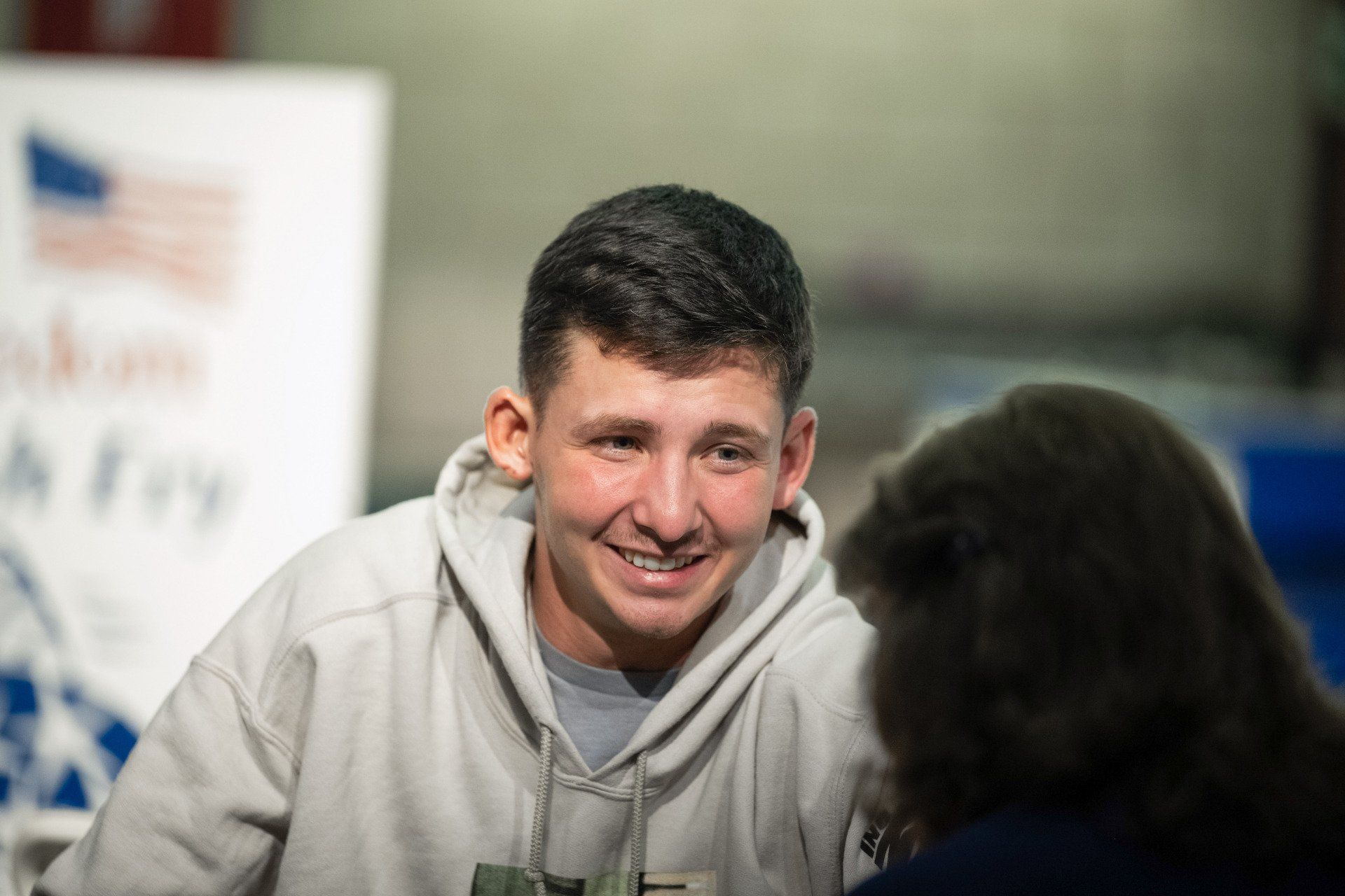A young man is sitting at a table talking to a woman.