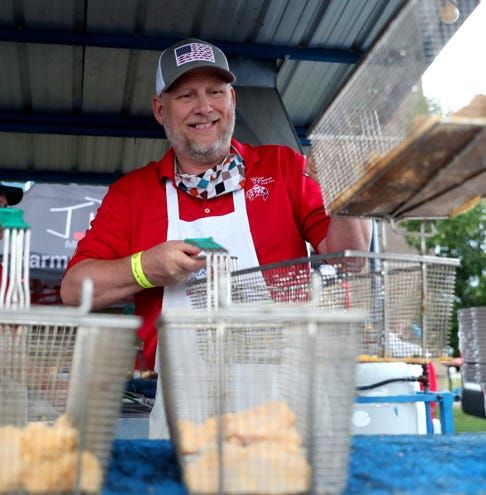 A man in a red shirt and white apron is preparing food