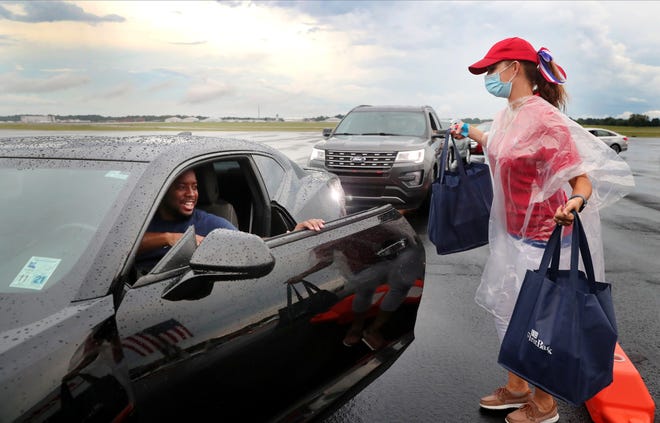 A woman in a red hat is standing next to a black car.