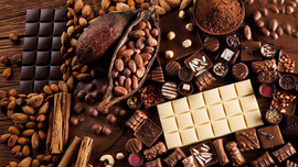 Surtido de barras de chocolate, granos de cacao y nueces sobre una superficie de madera.