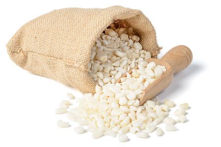 Bolsa de arpillera llena de maíz blanco picado; cuchara de madera.