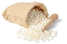 Bolsa de arpillera llena de maíz blanco picado; cuchara de madera.