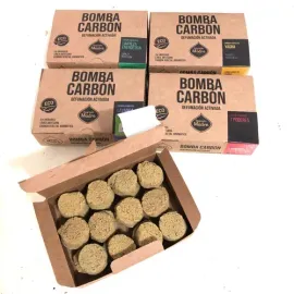 Cajas de briquetas de carbón activado “Bomba Carbon”, con una de las cajas abierta para exponer las briquetas.