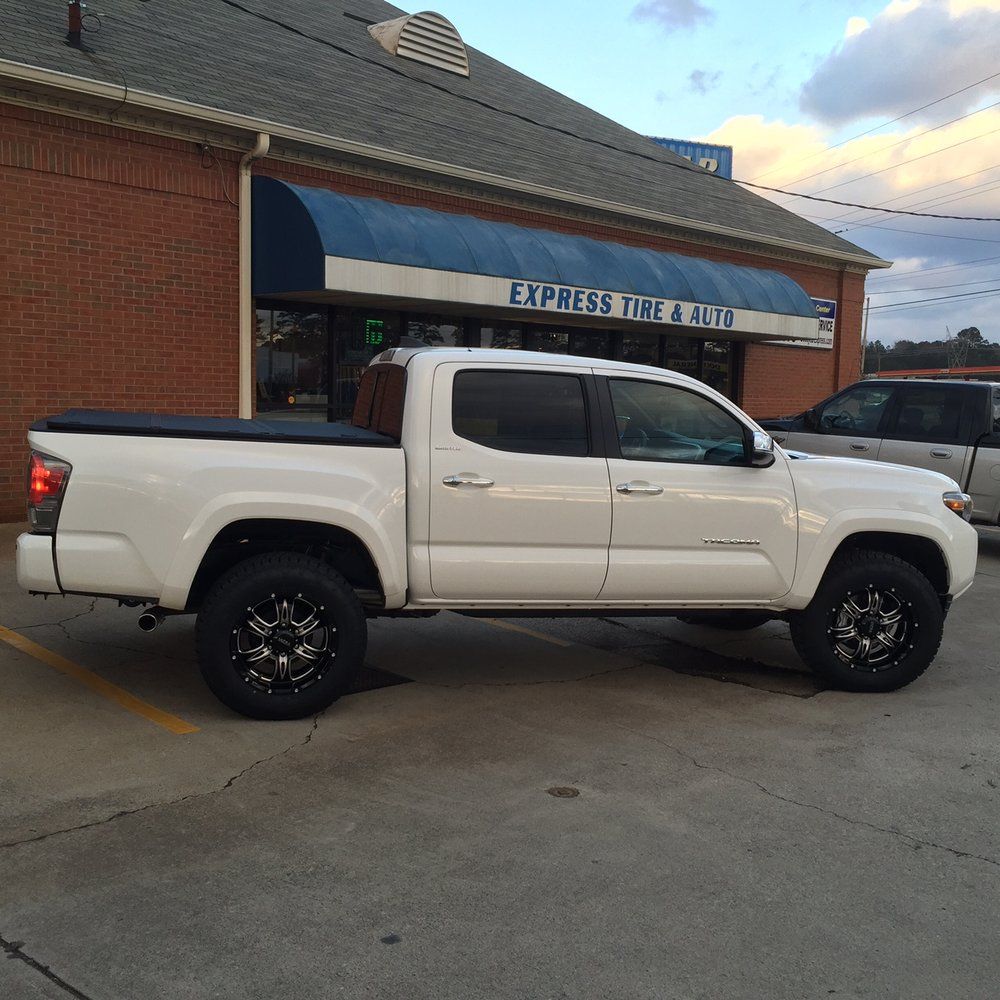 A white truck is parked in front of a store called express tire & auto A white truck is parked in front of a store called express tire & auto