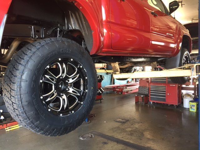 A red truck is sitting on a lift in a garage. A red truck is sitting on a lift in a garage.