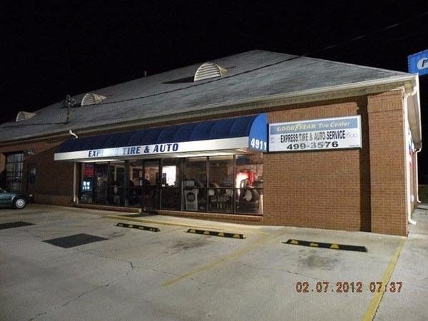 A brick building with a blue awning that says tire & auto