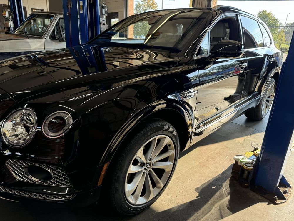 A black bentley is parked on a lift in a garage.