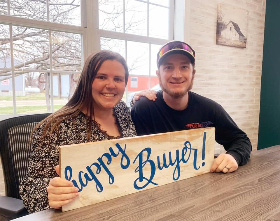 A man and a woman are holding a sign that says `` happy buyer ''.