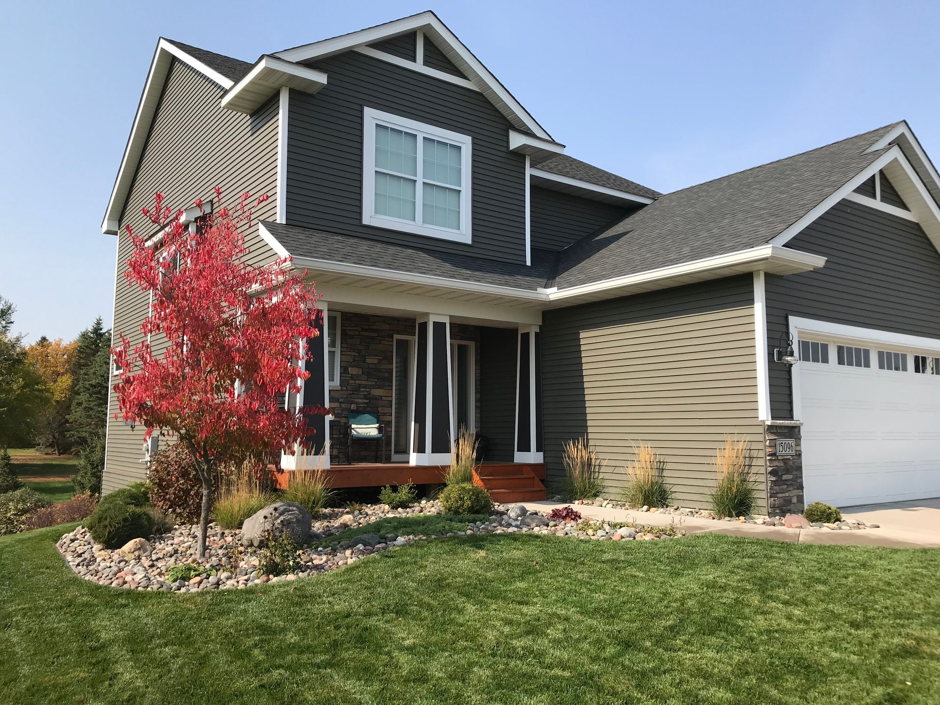 A large house with a rock garden with trees and plants. 