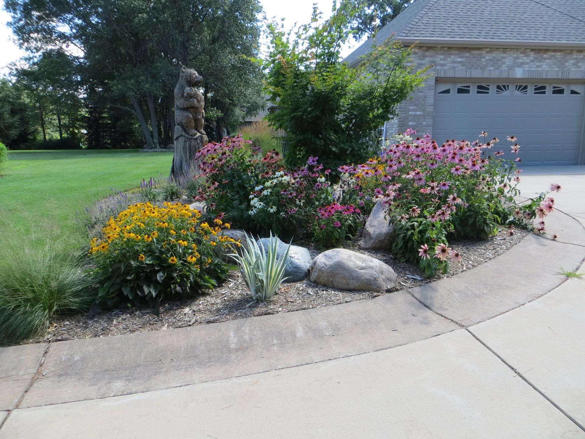 A garden with flowers and rocks in front of a garage door