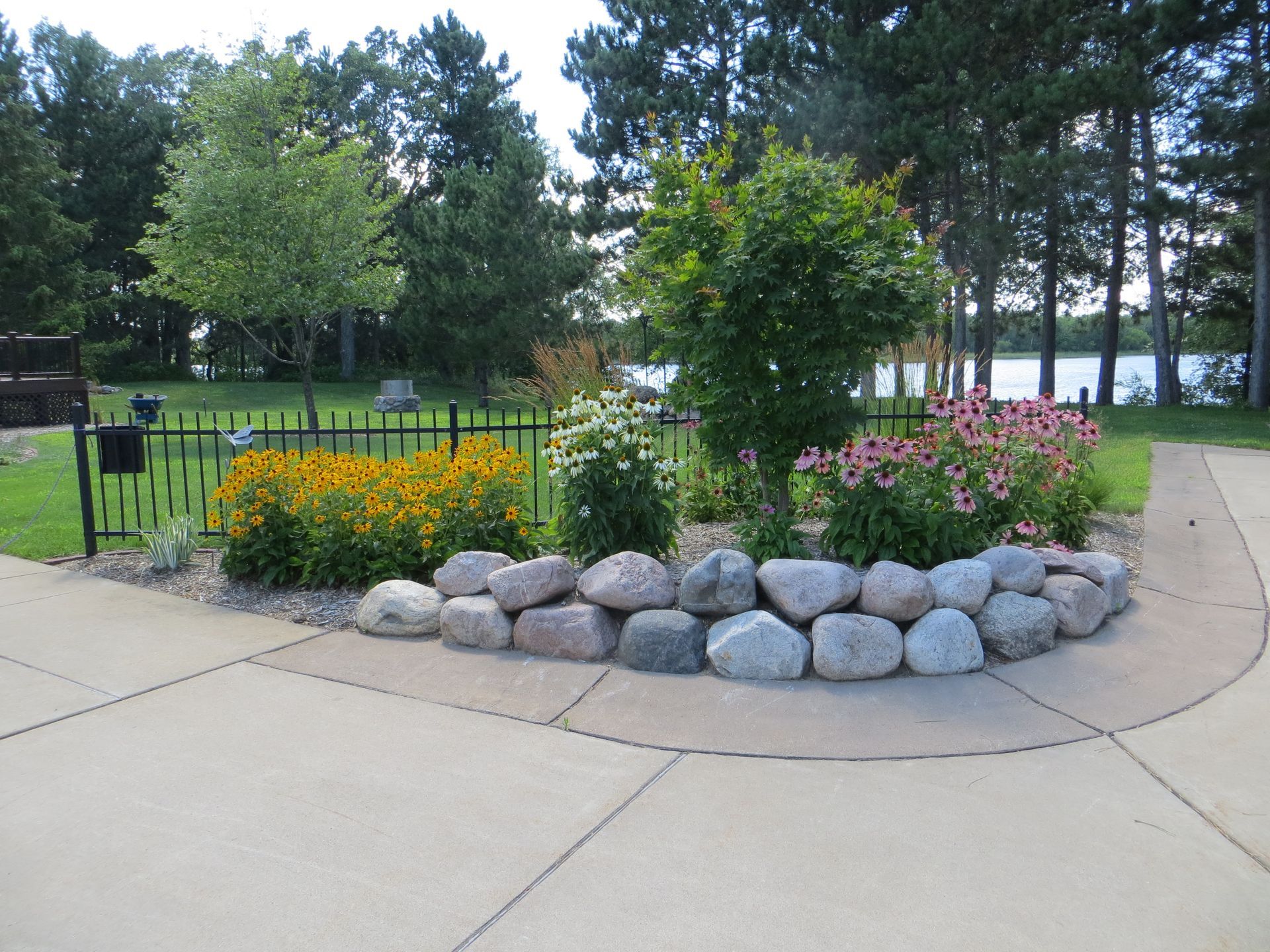 A garden with flowers and rocks in the middle of a driveway
