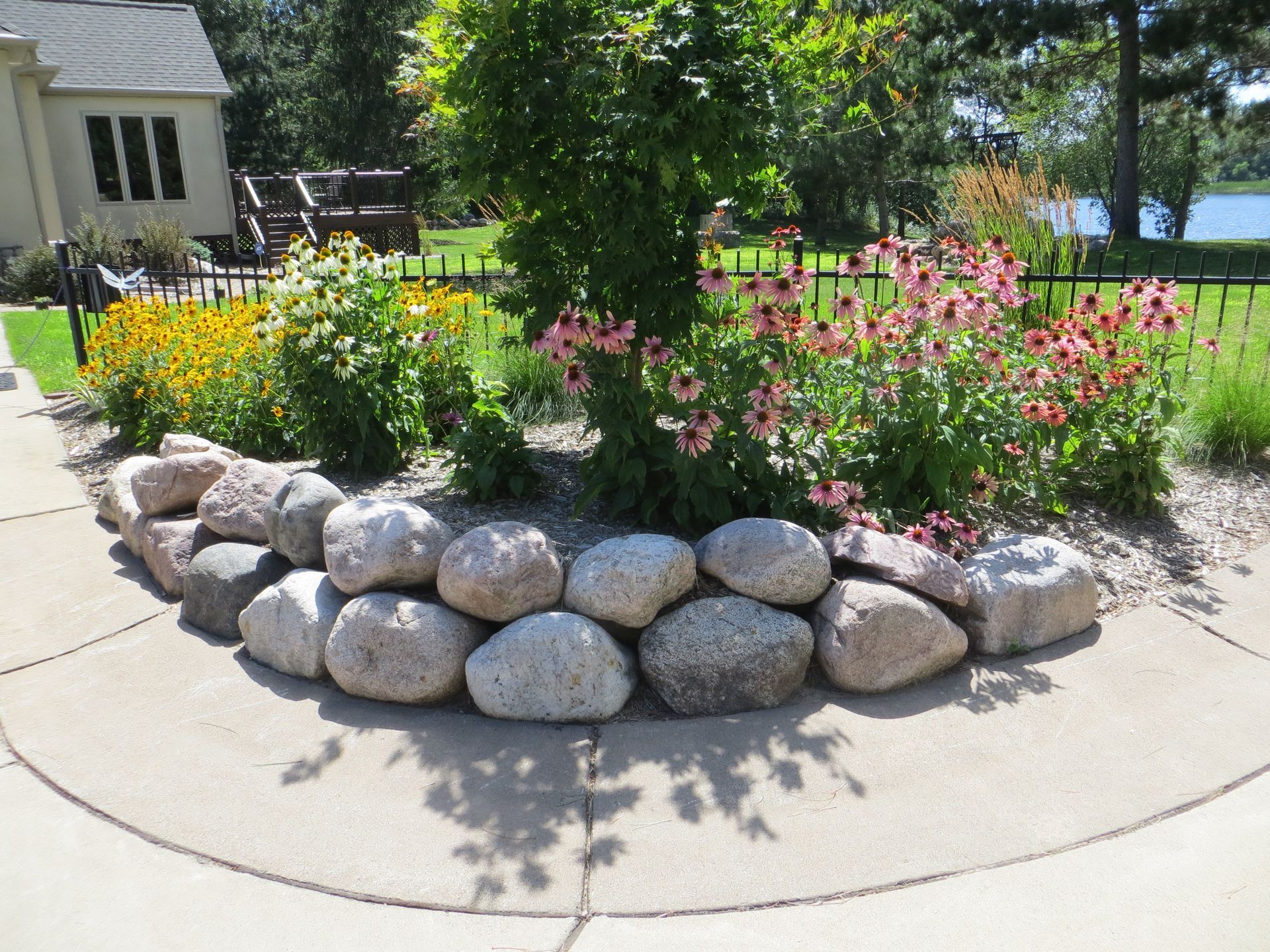 A garden with a rock retaining wall and flowers in the middle of it